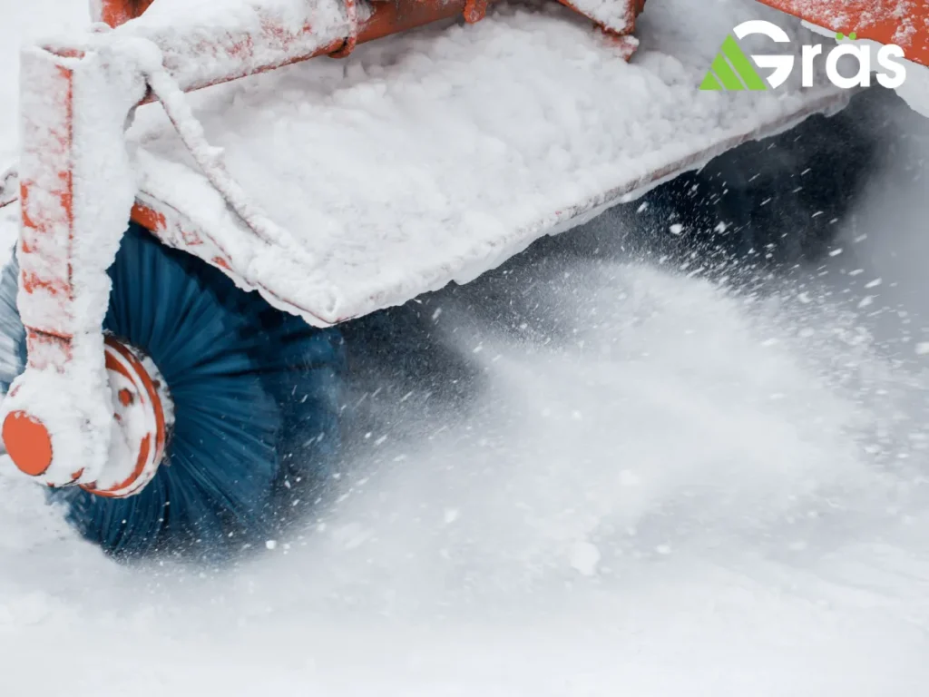 Snow removal machine brushing snow from a sidewalk