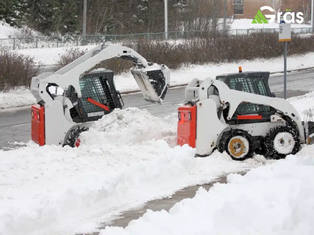 Commercial snowplow equipment removing snow from large parking lot during winter storm
